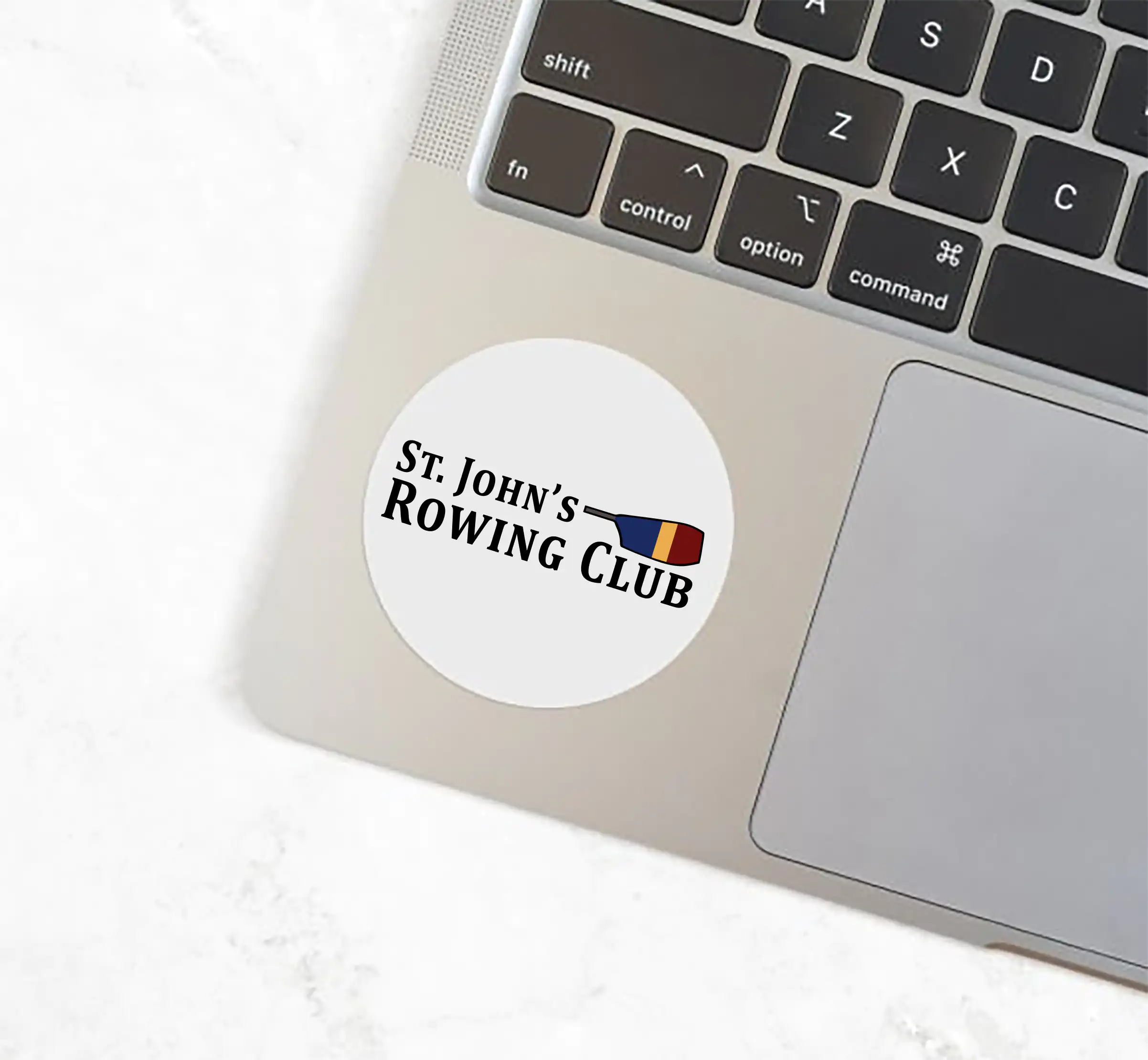 St. John's Rowing Club logo with a colorful rowing oar. A white 2" x 2" sticker on a laptop.