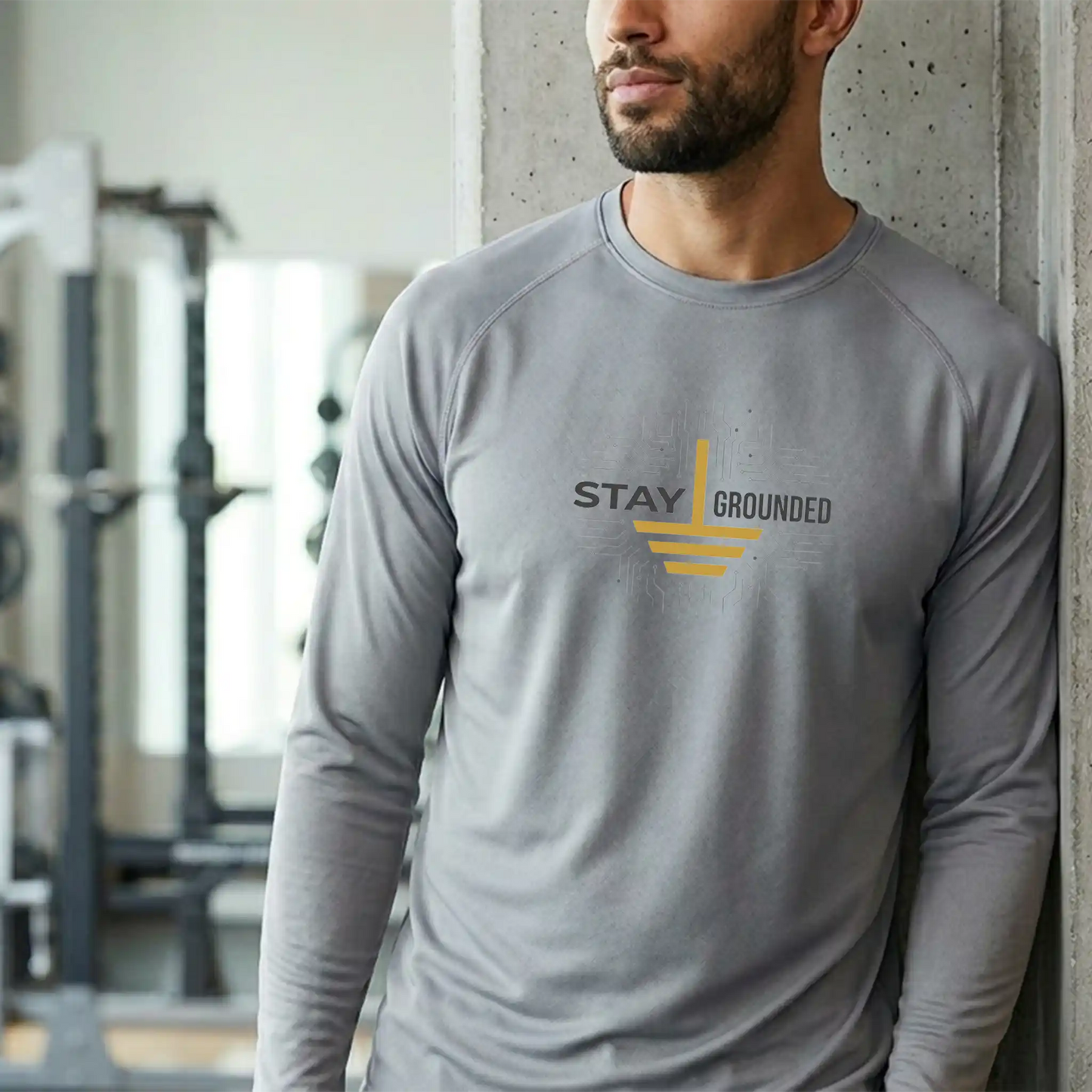 Male model in a concrete industrial gym wearing the long-sleeve CE10L Platinum performance shirt, featuring the professional slate and gold ground design.