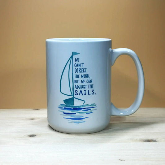 Nautical home decor 15oz ceramic coffee cup with motivational boating illustration on a pine wood stand.