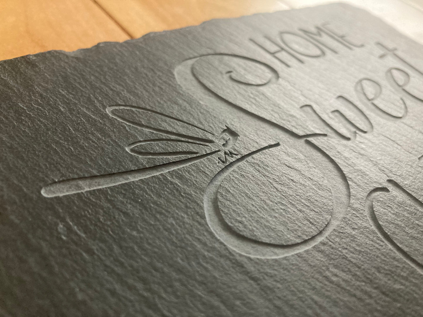 A closeup, side profile of Home Sweet Clinic sign with dragonfly. Showing the depth of the sand-carved slate sign.