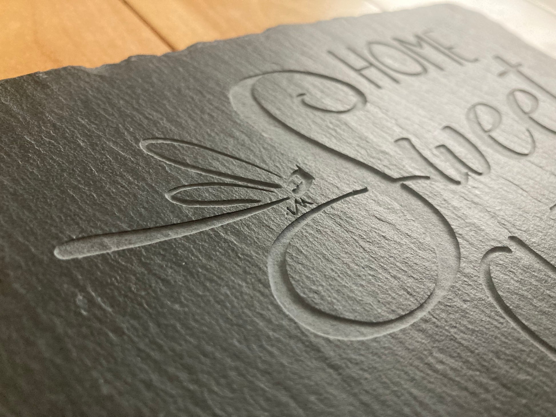 A closeup, side profile of Home Sweet Clinic sign with dragonfly. Showing the depth of the sand-carved slate sign.